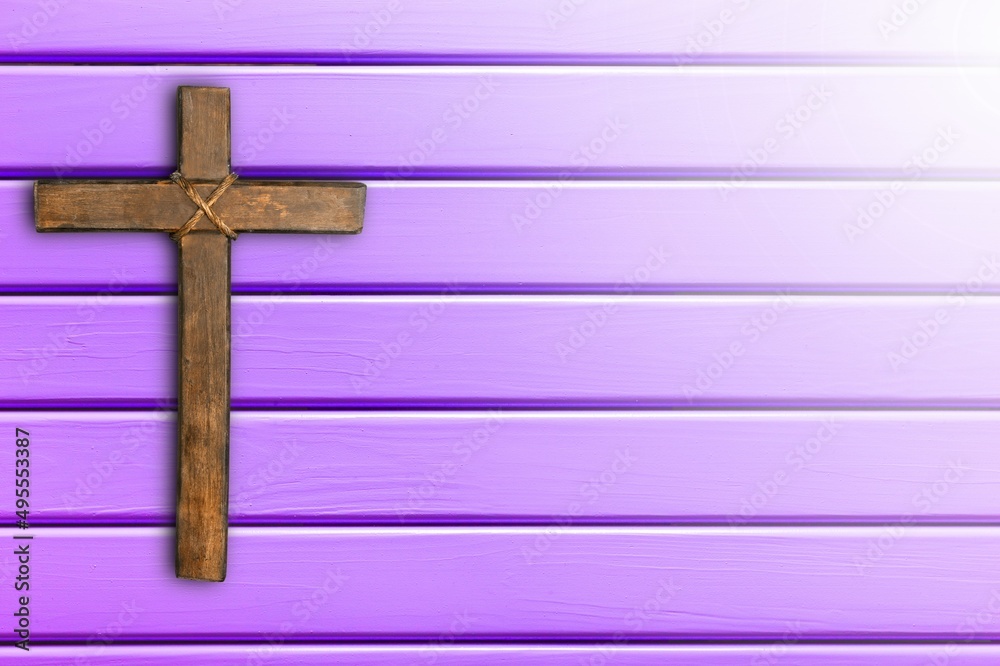 Wooden christian cross on purple background.
