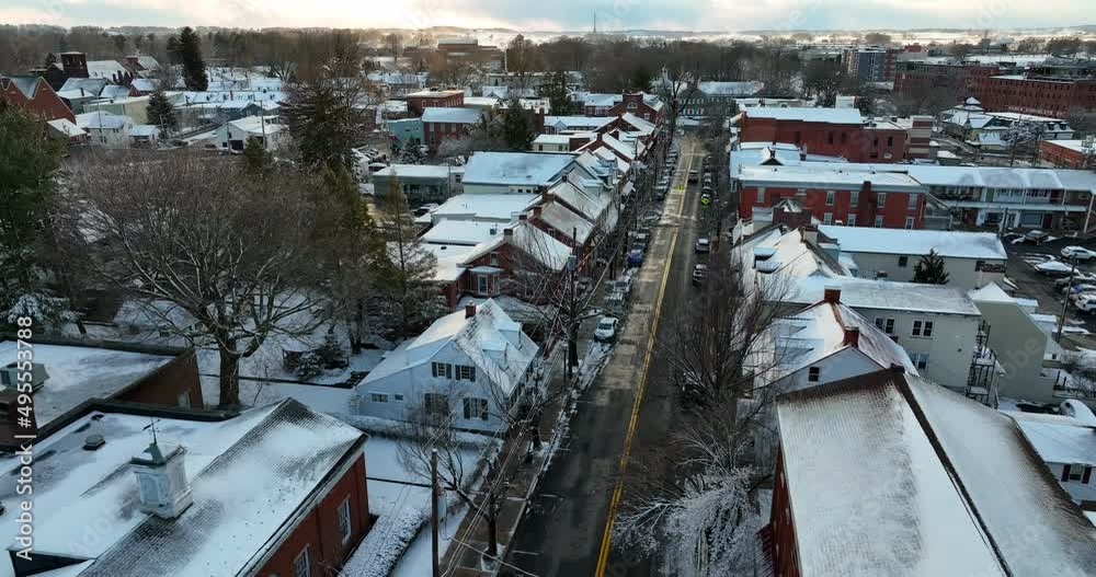 American small town covered in winter snow. Rooftop view at sunset above road street. Quiet aerial establishing shot. American small town covered in winter snow. Rooftop view at sunset above road street. Quiet aerial establishing shot.