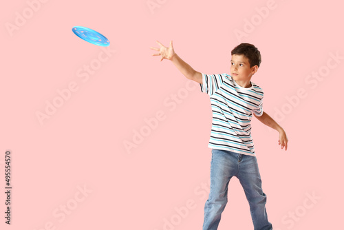 Funny little boy playing frisbee on color background photo