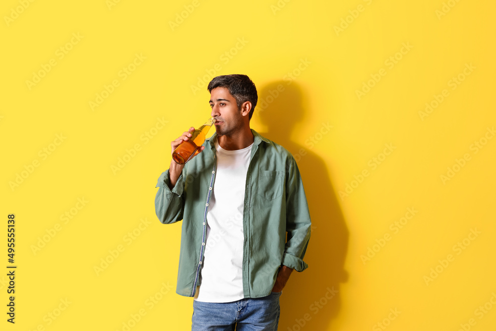 Handsome man drinking beer on yellow background Handsome man drinking beer on yellow background