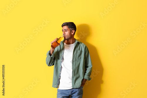 Handsome man drinking beer on yellow background © Pixel-Shot