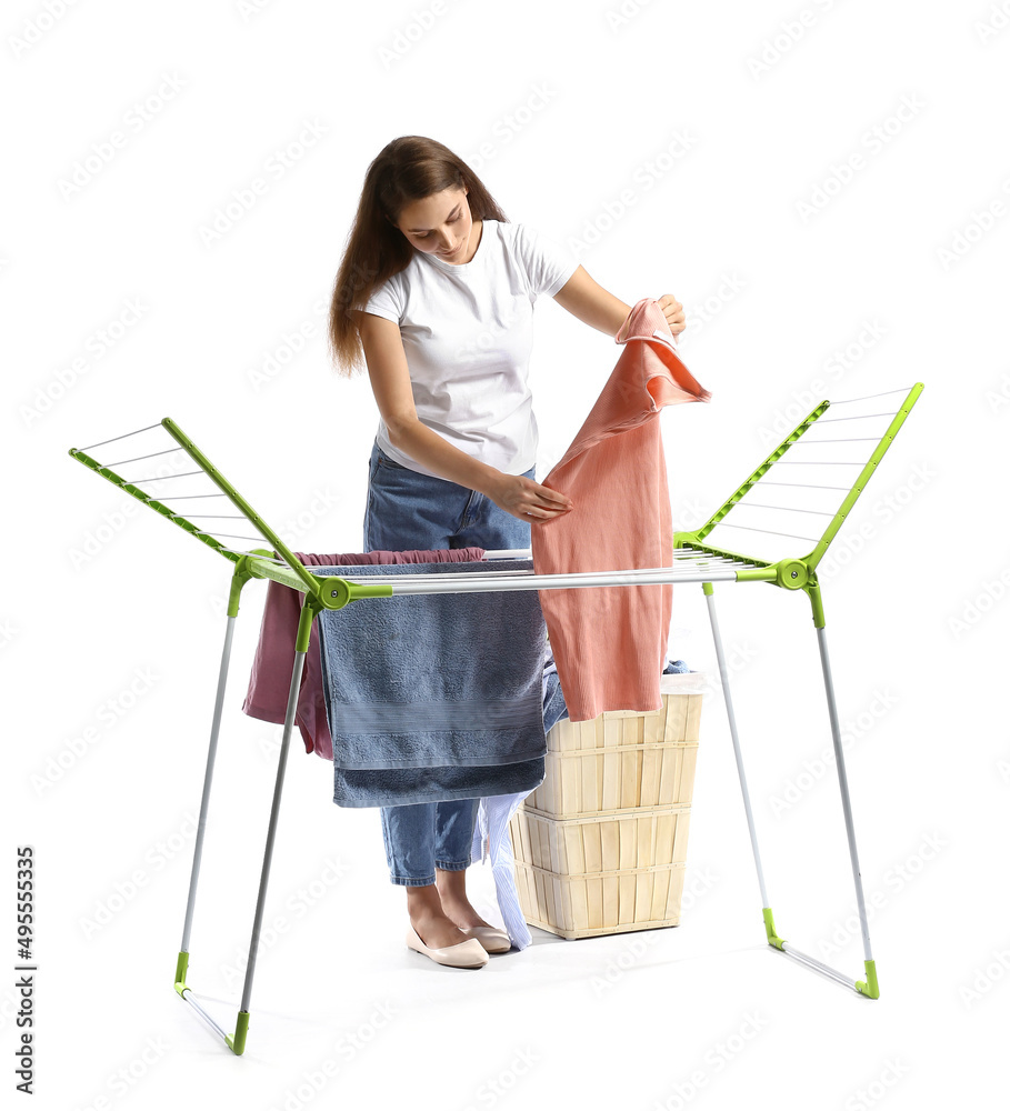 Beautiful woman hanging clean laundry on dryer against white background