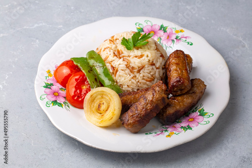 Inegol Kofte or Tekirdag Kofte from Turkish dishes. Served on a plate with rice pilaf, grilled tomatoes and peppers.