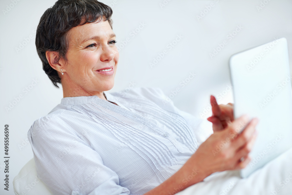 Mature woman using tablet PC at home. Relaxed mature woman using tablet PC while sitting on couch. Mature woman using tablet PC at home. Relaxed mature woman using tablet PC while sitting on couch.