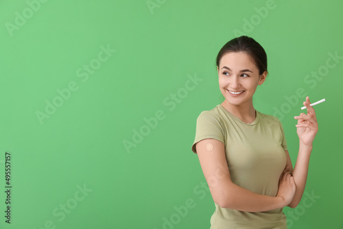 Young woman with applied nicotine patch and cigarette on color background. Smoking cessation photo