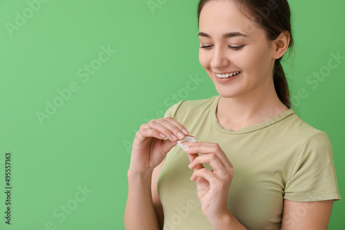 Happy woman with nicotine patch on color background. Smoking cessation photo