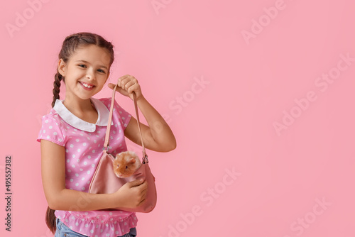 Little girl with cute guinea pig in bag on pink background photo