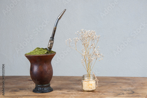 chimarrão cuia next to a flower vase on top of a wooden table photo