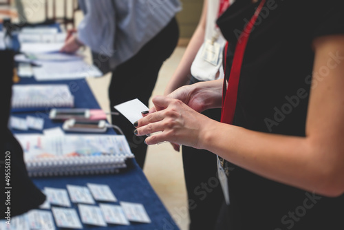 Process of checking in on a conference congress forum event  registration desk table  visitors and attendees receiving a name badge and entrance wristband bracelet and register electronic ticket