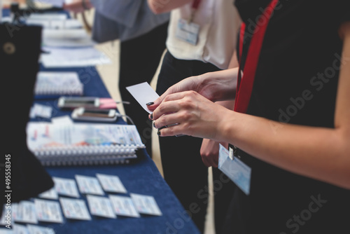 Process of checking in on a conference congress forum event, registration desk table, visitors and attendees receiving a name badge and entrance wristband bracelet and register electronic ticket © tsuguliev