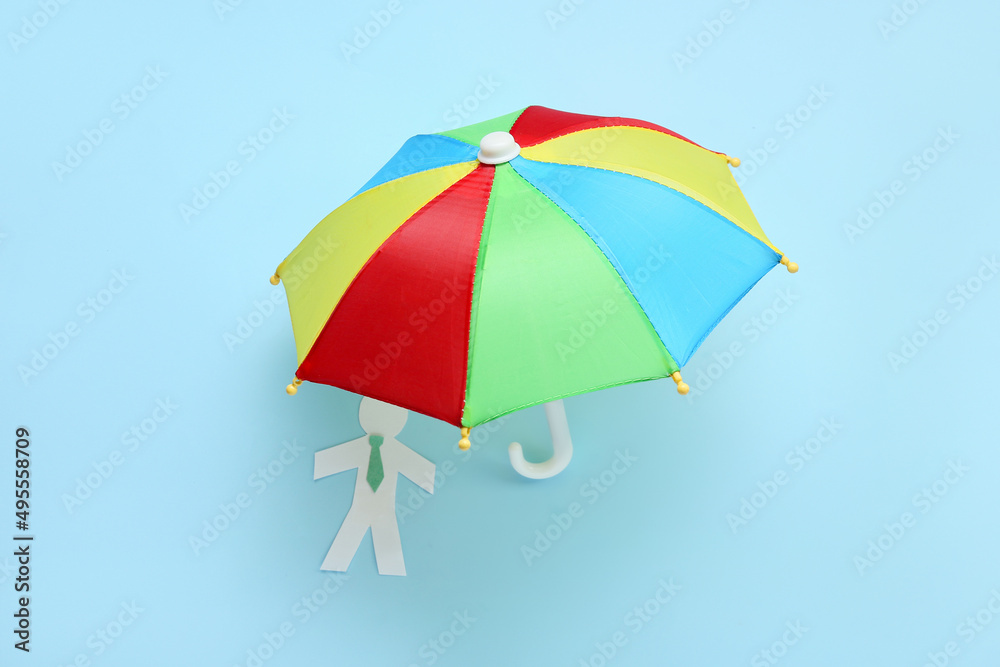 Open umbrella and paper human figure on color background