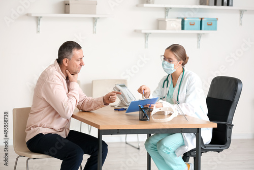 Ill man with sore throat visiting doctor in clinic