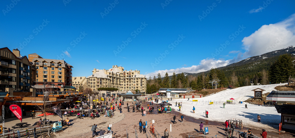 Fototapeta premium A panoramic image of the Whistler Village on a spring day with skiers on Whistler Mountain.