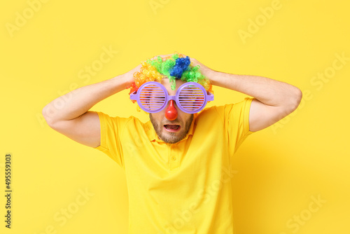 Funny young man in disguise on yellow background. April fools' day celebration