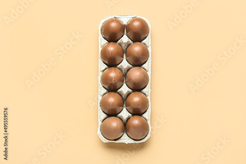 Holder with delicious chocolate eggs on beige background