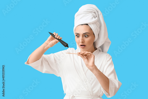 Shocked young woman with activated charcoal tooth paste and brush on blue background