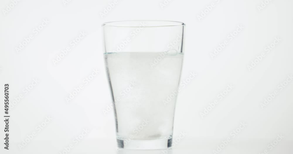 Effervescent tablet falls and dissolve in glass of water in close up Effervescent tablet falls and dissolve in glass of water in close up