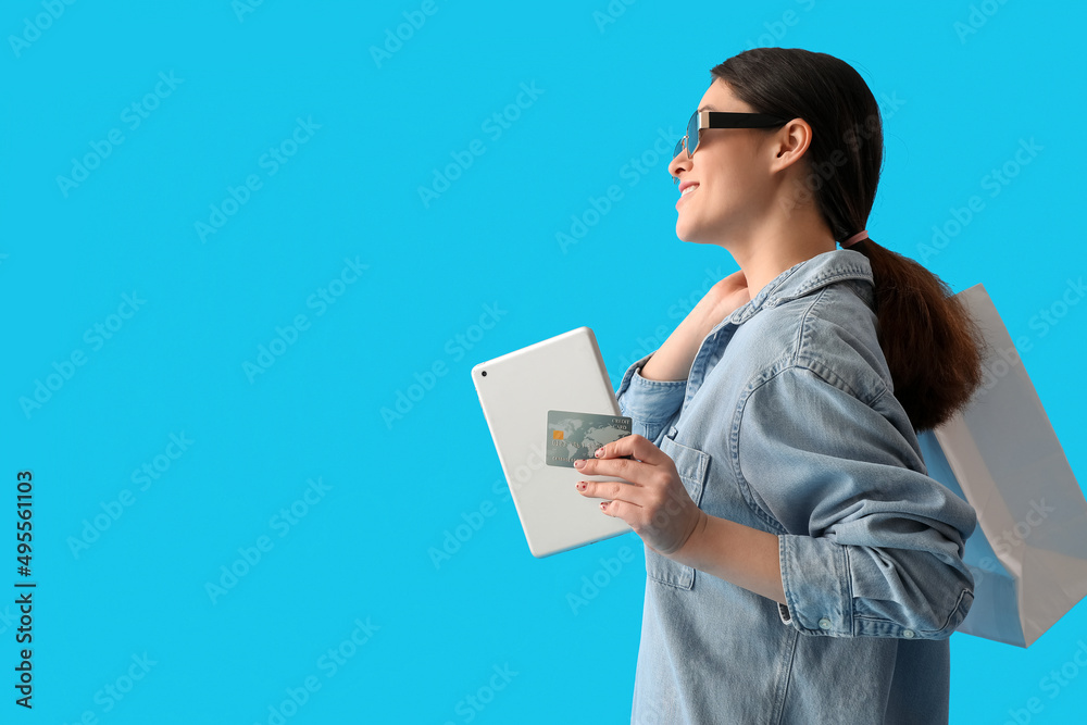 Young woman with tablet computer, credit card and shopping bag on color background Young woman with tablet computer, credit card and shopping bag on color background