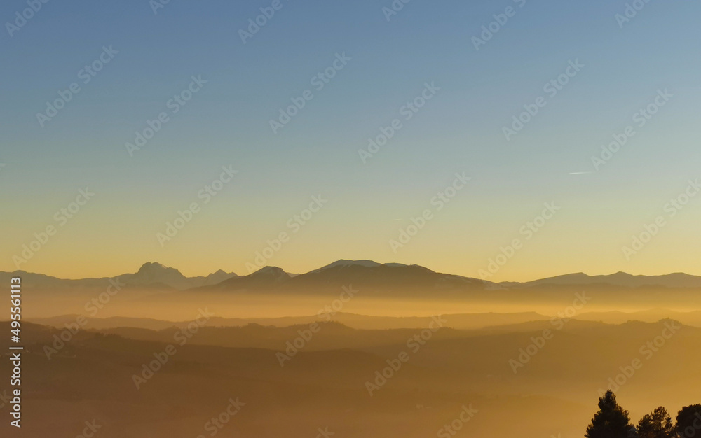 Un mare di luce dorata al tramonto colora le montagne e le colline e riempie le valli 