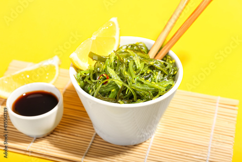 Bowl with healthy seaweed salad on yellow background