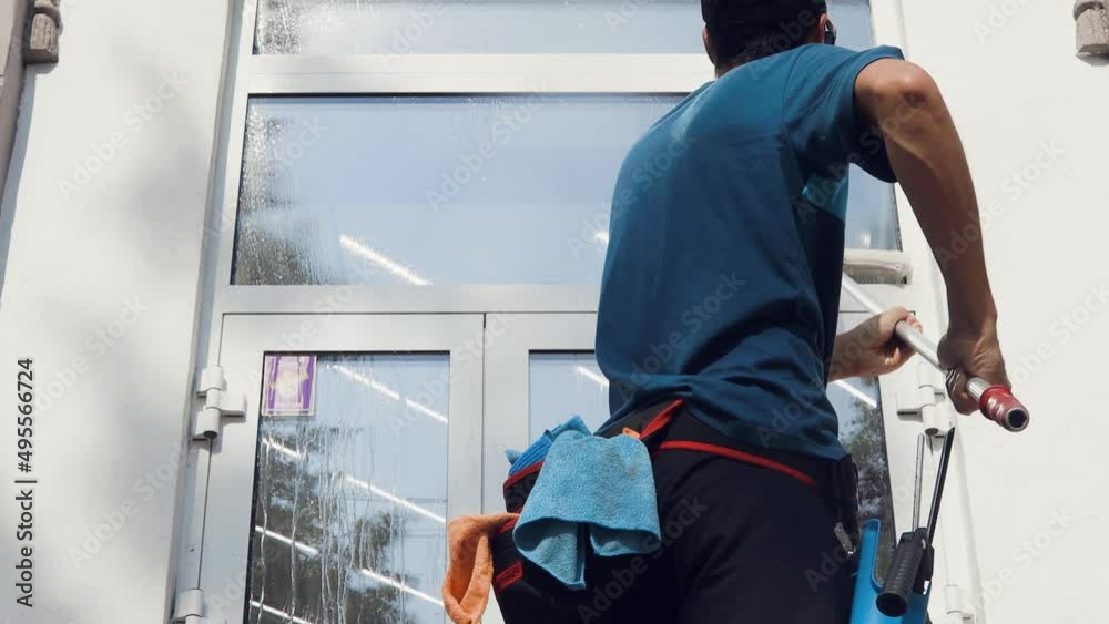 A professional worker from a cleaning company washes the company's windows with special chemicals A professional worker from a cleaning company washes the company's windows with special chemicals