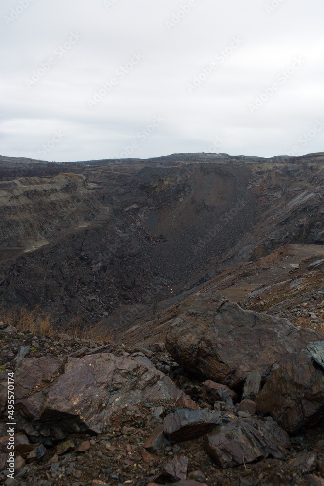 Old abandoned huge coal pit. Nature pollution. Ruins and stones. Ruins and huge mountains of dirty rock. 
