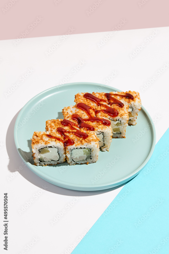 Sushi roll with chicken, cucumber and cheese inside, crispy onion outside. Maki sushi with chicken on ceramic dish. Alternative maki sushi on coloured background in minimal style. Sushi no fish. Sushi roll with chicken, cucumber and cheese inside, crispy onion outside. Maki sushi with chicken on ceramic dish. Alternative maki sushi on coloured background in minimal style. Sushi no fish.