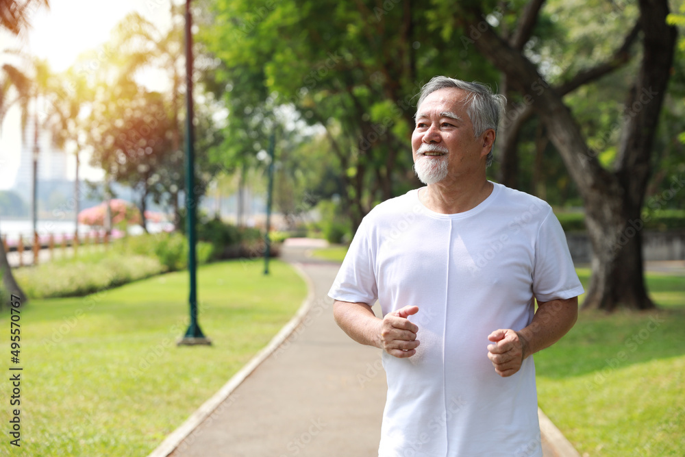 Happy and smiling asian senior man doing exercise and jogging or walking with relaxation for healthy in park outdoor after retirement during summer time. Health care elderly outdoor lifestyle concept. Happy and smiling asian senior man doing exercise and jogging or walking with relaxation for healthy in park outdoor after retirement during summer time. Health care elderly outdoor lifestyle concept.