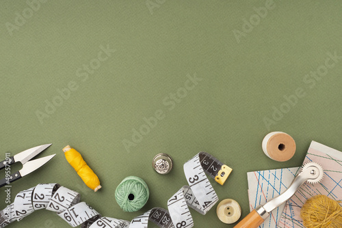 Fotografia Pattern, fabric and sewing accessories on a green paper background, flat, lay, top view, copy space