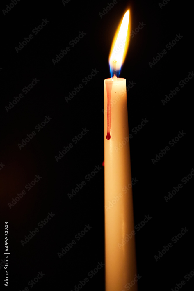One candle burns in the dark. The concept of loneliness and self-belief. Prayers to the Lord. Vertical photo. One candle burns in the dark. The concept of loneliness and self-belief. Prayers to the Lord. Vertical photo.