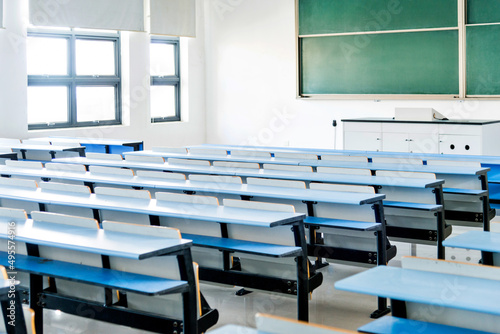 Bright university classroom with blue desks and chalkboard