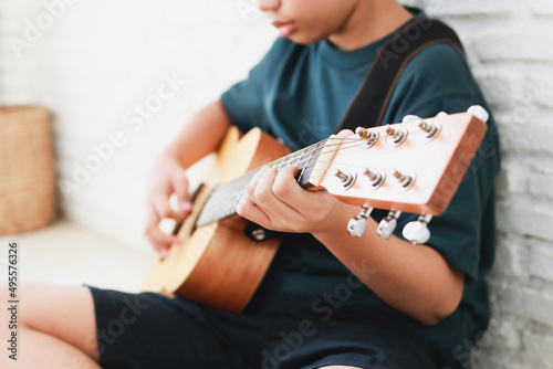 Asian boy playing guitar in the house. music learning concept, music proficiency training