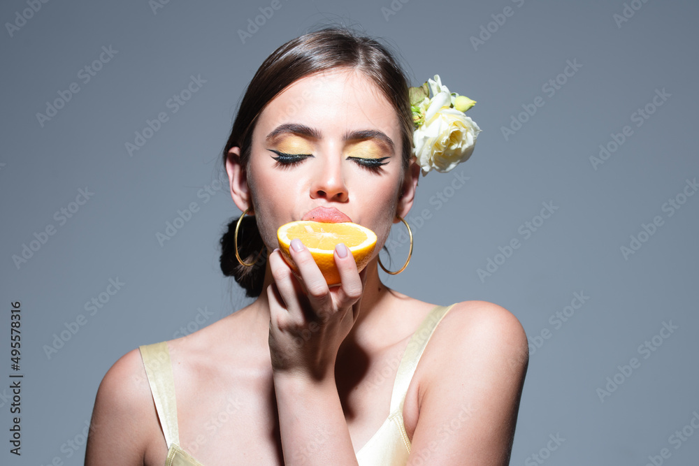 Portrait of pretty dreamy natural girl eating pieces of orange, enjoying smell freshness with close eyes, isolated on gray background. Portrait of pretty dreamy natural girl eating pieces of orange, enjoying smell freshness with close eyes, isolated on gray background.