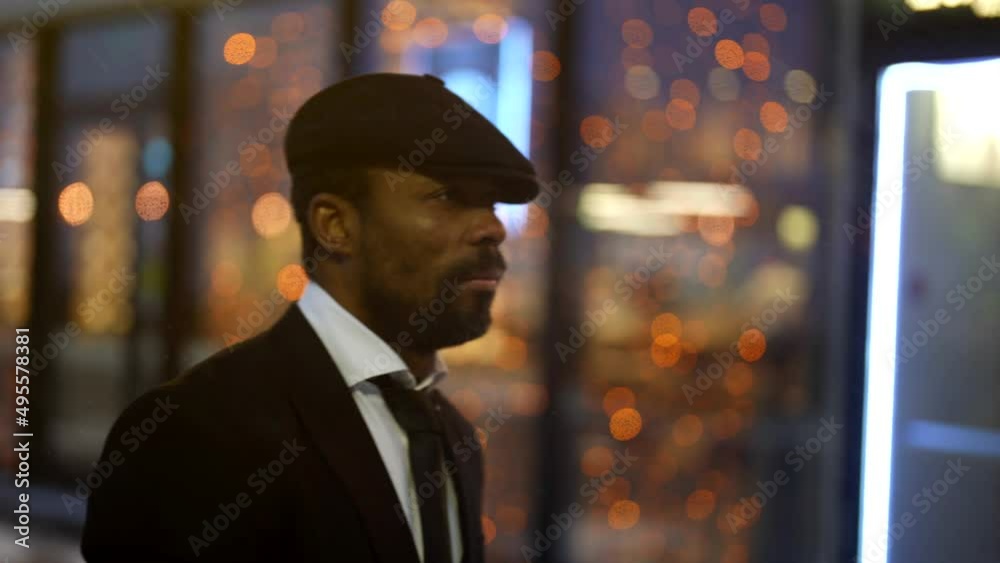 handsome black man is walking in megapolis in night, elegant guy in black suit and cap is strolling handsome black man is walking in megapolis in night, elegant guy in black suit and cap is strolling