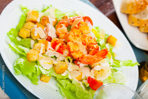 Piquant Caesar salad with green lettuce, crispy croutons, Parmesan cheese and grilled shrimps