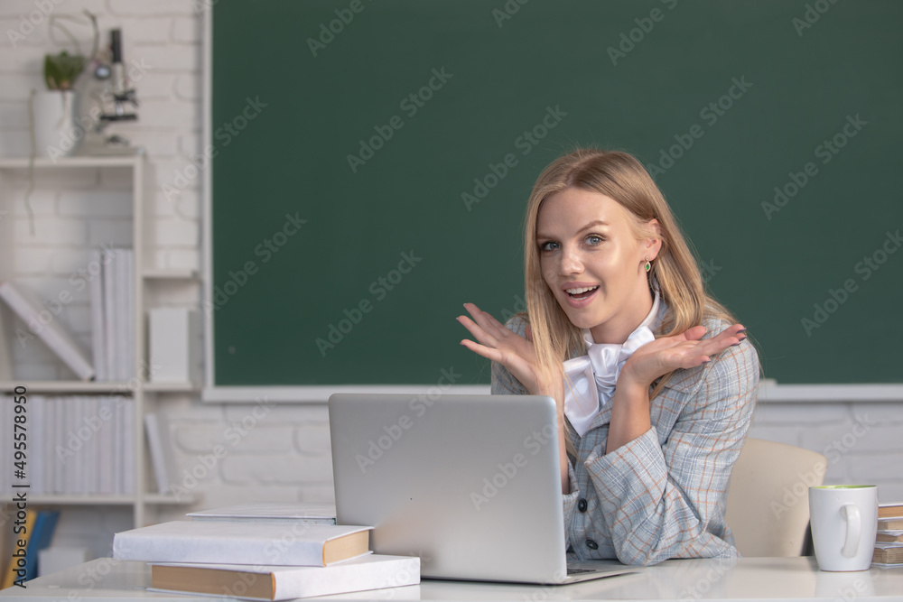 Portrait of a young, confident and amazed female student studying in school classroom. Creative young smiling female student using laptop. Portrait of a young, confident and amazed female student studying in school classroom. Creative young smiling female student using laptop.
