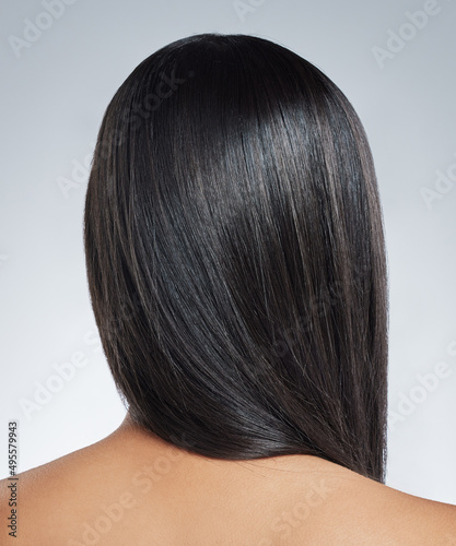 Healthy hair is seen in the shine. Shot of an unrecognisable woman standing alone in the studio.