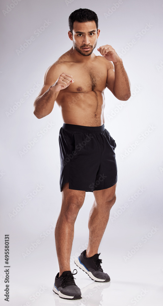 Follow through with determination. Shot of a young man practicing his punches against a studio background. Follow through with determination. Shot of a young man practicing his punches against a studio background.