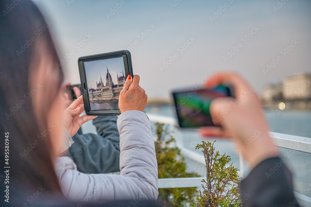 Tourists taking pictures of Budapest Parliament at sunset, Hungary