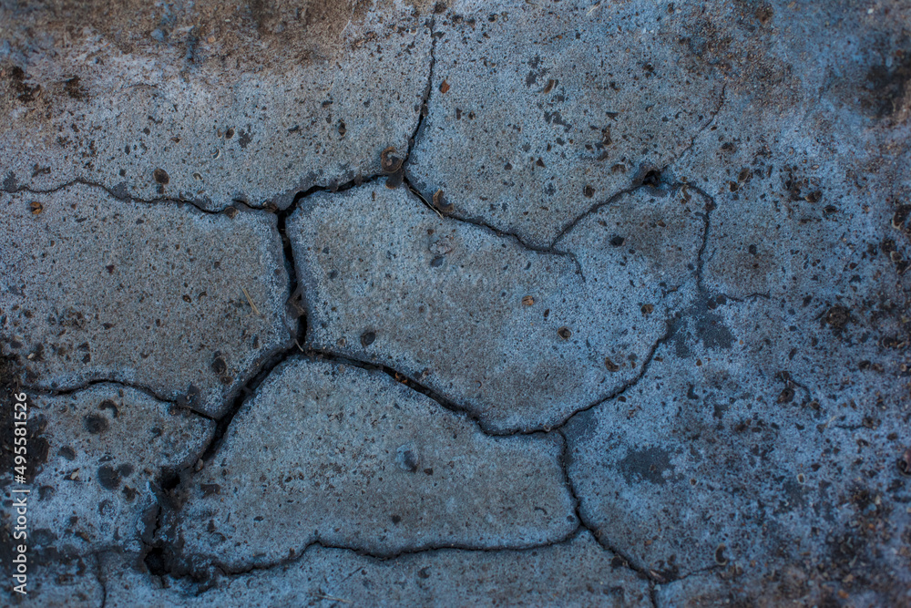 Fototapeta premium Texture of the dried earth. Dark gray background with cracks and hollows. Drought and lack of moisture in the soil. The consequences of abnormal heat. Environmental disaster. Global warming.
