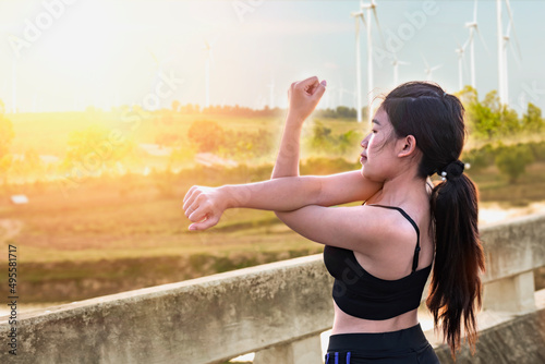 Beautiful woman exercising in the morning with mist and windmills in the background.