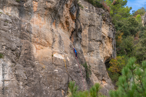 A woman, backview, climbs on a rock wall at Siurana. Priorat, Catalonia, Spain. photo