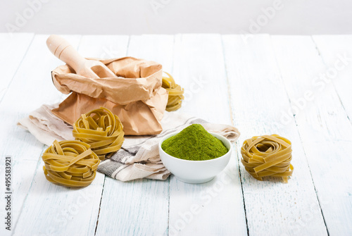 uncooked taglatelle pasta and ingredients: grounded spinach powder and whole wheat flour photo