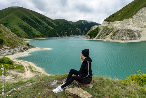 A girl on the background of Lake Kezenoy-am in the Caucasus mountains in Chechnya, Russia June 2021.