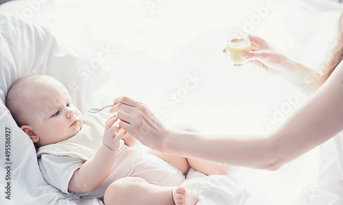 Maternity concept. A young mother feeds her little baby. First lure and breastfeeding. Family in white clothes.