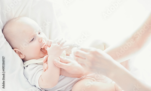 Maternity concept. A young mother feeds her little baby. First lure and breastfeeding. Family in white clothes.