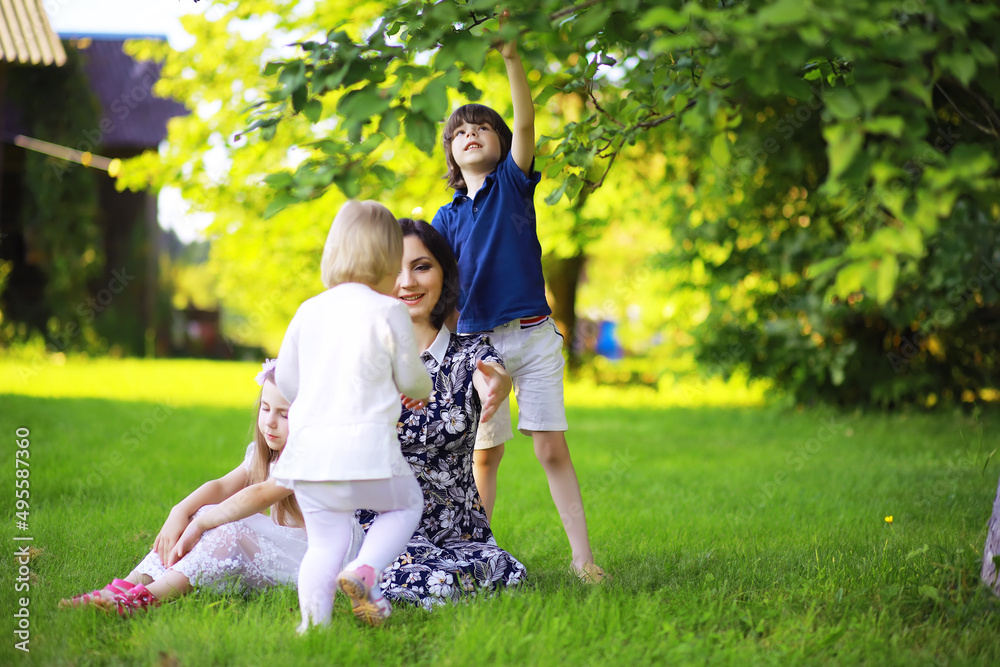 Obraz premium Young large family on a summer morning walk. Beautiful mother with children is playing in the park.