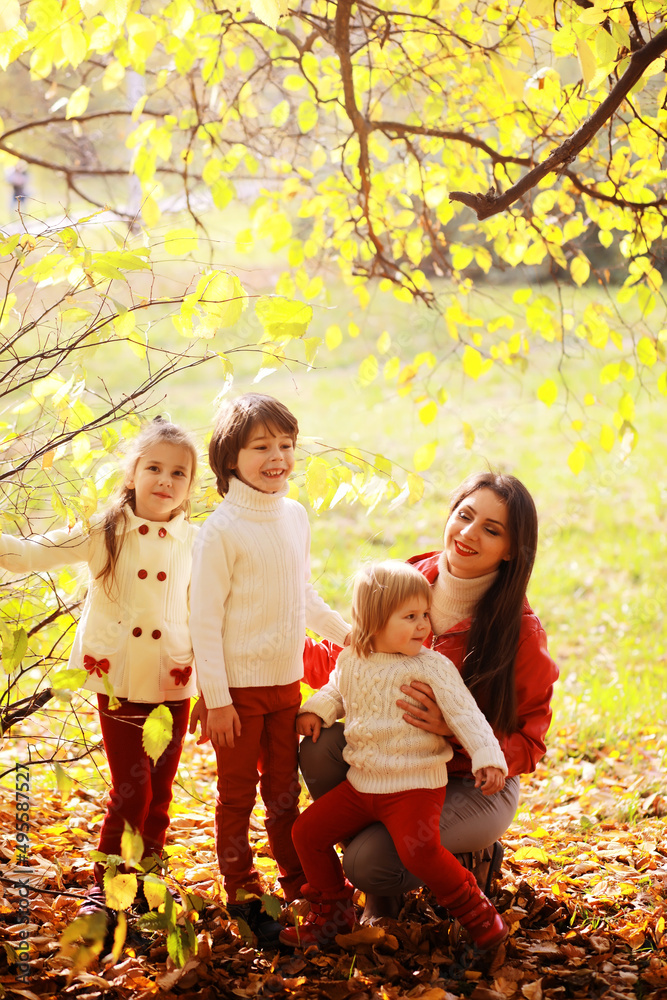 Fototapeta premium Young family on a walk in the autumn park on a sunny day. Happiness to be together.
