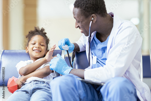 A young African girl sits for the doctor to check her health and plays with her mobile phone.