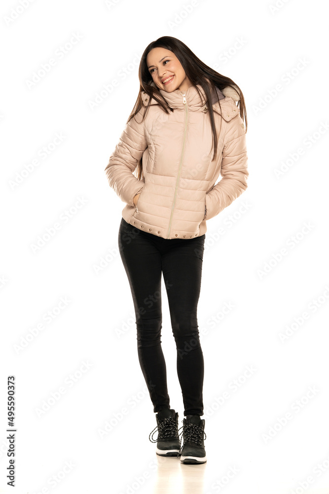 Front view of a young woman in winter jacket, and black jeans posing on a white background Front view of a young woman in winter jacket, and black jeans posing on a white background